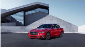 Red sports car parked in front of modern concrete building.