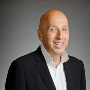 Professional headshot of a smiling bald man in a black blazer.