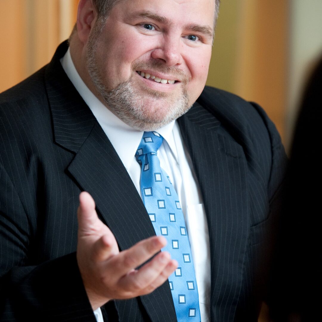 Smiling man in a suit engaging in conversation.
