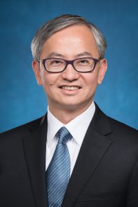 Professional man in suit and tie smiling with glasses.