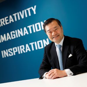 Businessman smiling in front of a blue wall with motivational words.