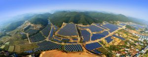 Vast solar panel array on hilly terrain under clear sky.