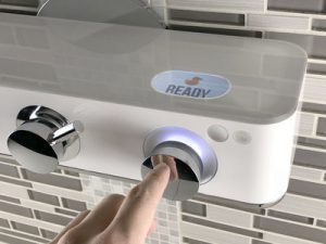 Finger pressing a glowing button on a sleek white device.