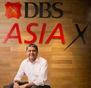 Man in white shirt smiling in front of DBS AsiaX sign.