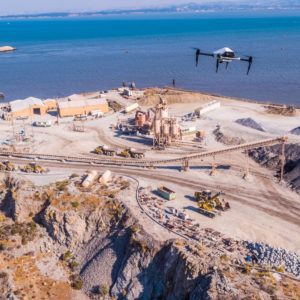 Coastal construction site with heavy machinery and workers near the shore.