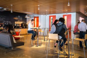 People sitting and working in a modern cafe with bar stools and a warm ambiance.