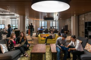 People socializing and working in a modern lounge area with cozy seating.