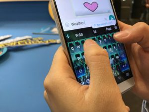Person typing a heart emoji on a smartphone keyboard.