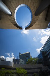 Looking up at skyscrapers around a circular opening in modern architecture.