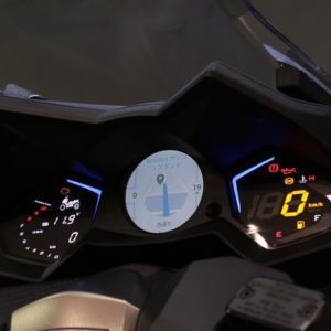 Close-up of a motorcycle digital and analog dashboard at night.