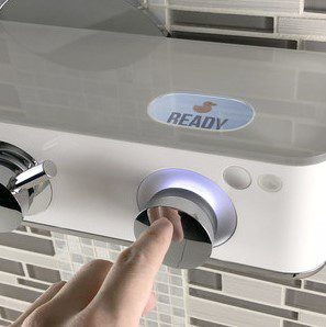 Finger pressing a button labeled READY on a modern appliance.