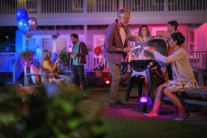 People enjoying a vibrant outdoor party with colorful lights and music.