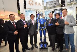 Group of five men standing with a blue humanoid robot indoors.