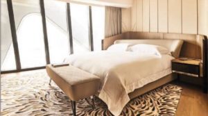 Cozy hotel room with a large bed and a cushioned bench.