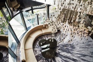 Modern indoor spiral staircase with artistic hanging decor.
