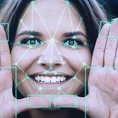 A woman smiling with facial recognition grid overlay on her face.