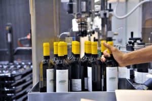 Bottling line filling bottles with yellow-capped wine bottles.