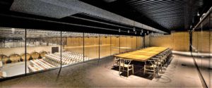 Modern interior with wooden tables and chairs under a dark ceiling.