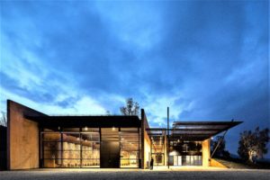 Modern building with glass walls under a dramatic evening sky.