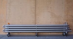 Metal pipes mounted on a concrete wall with visible stains and marks.