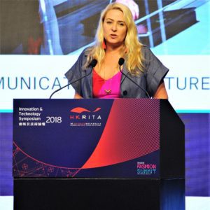 A woman speaks at a conference podium with a microphone.