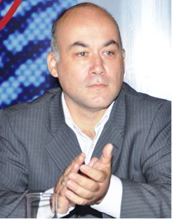 Man in a suit clapping his hands indoors.