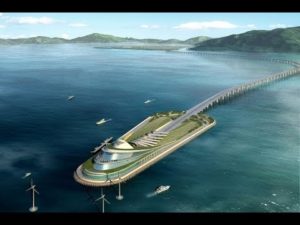 A futuristic bridge extending over water to a green, landscaped island with boats nearby.