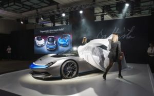 Unveiling of a sleek, futuristic electric car at an auto show.