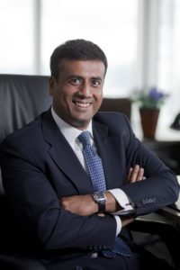 Confident businessman in a suit with arms crossed, smiling.