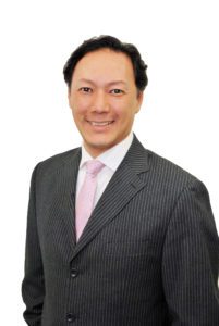 Professional man in a striped suit and pink tie smiling confidently.