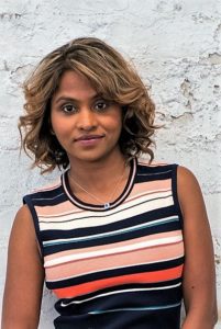 Young woman with curly hair wearing a striped sleeveless top.
