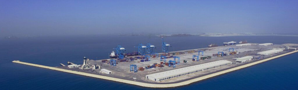 Aerial view of a large industrial port with cranes and containers.