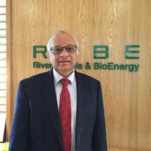 Professional man in a suit standing in front of a bioenergy company sign.