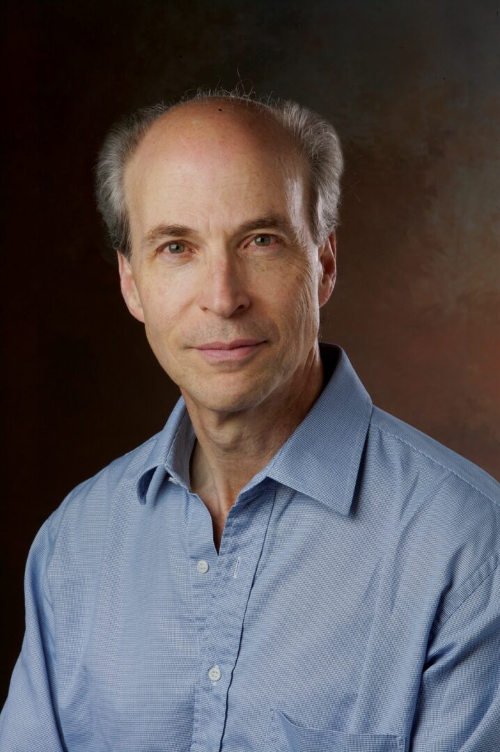 Portrait of a middle-aged man in a blue shirt with a neutral expression.