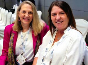 Two women smiling, wearing conference badges.