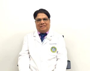 Doctor in white coat sitting against a plain background.