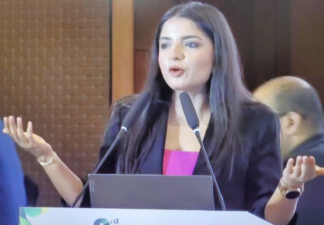 A woman speaks passionately at a podium with two microphones.