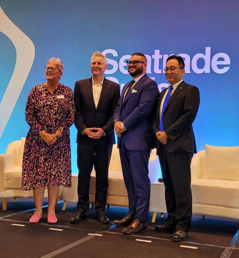 Four professionals stand on stage at a Sentade event, smiling for a group photo.