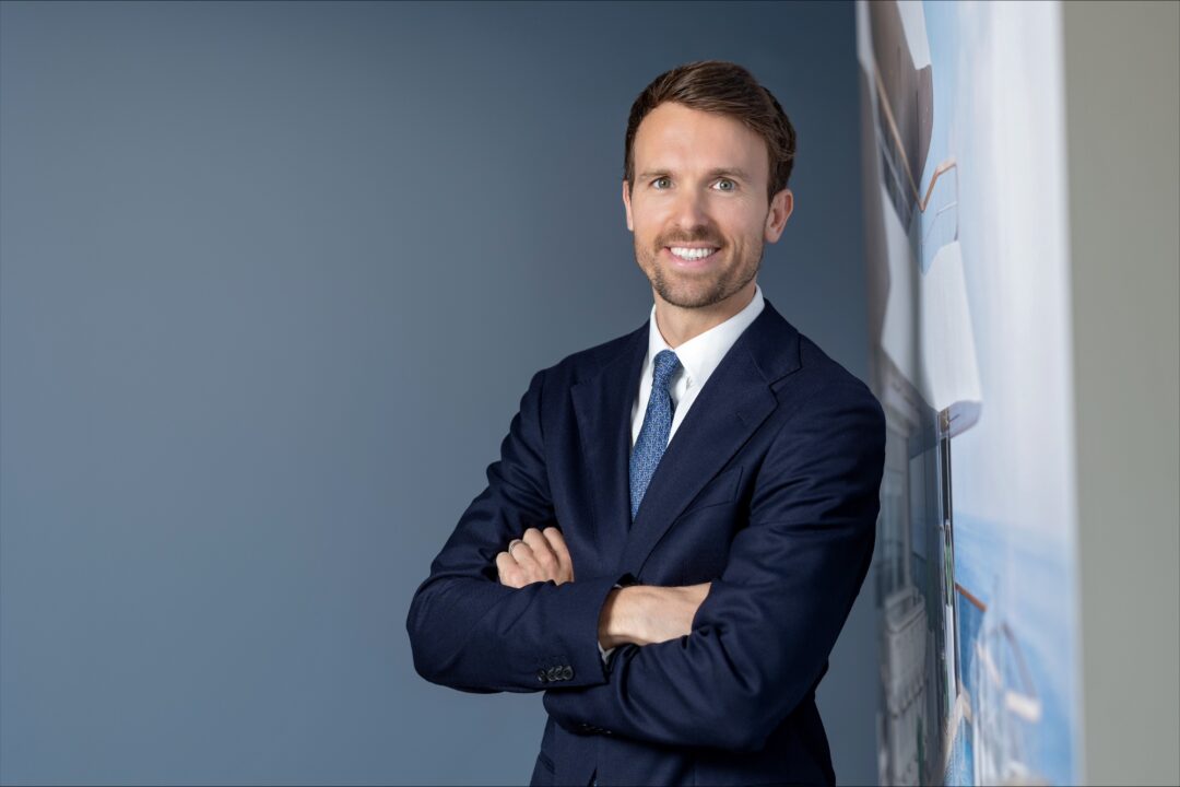 Confident man in a suit smiling with arms crossed.