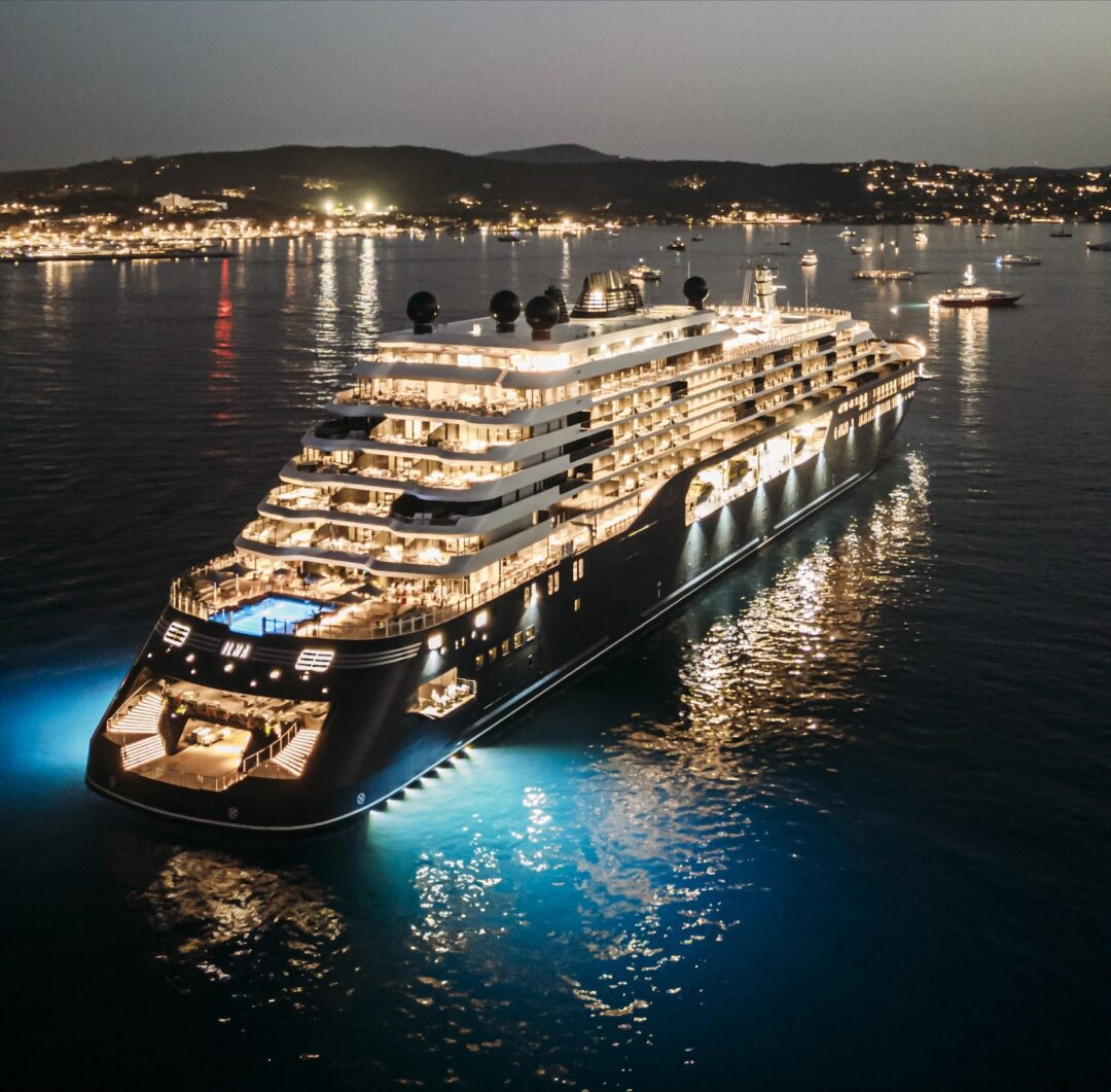 Luxurious cruise ship illuminated at night on calm waters.