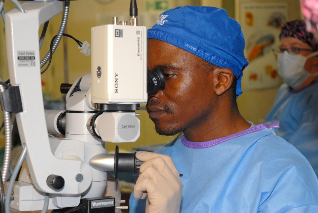 Medical professional using a microscope during a procedure.