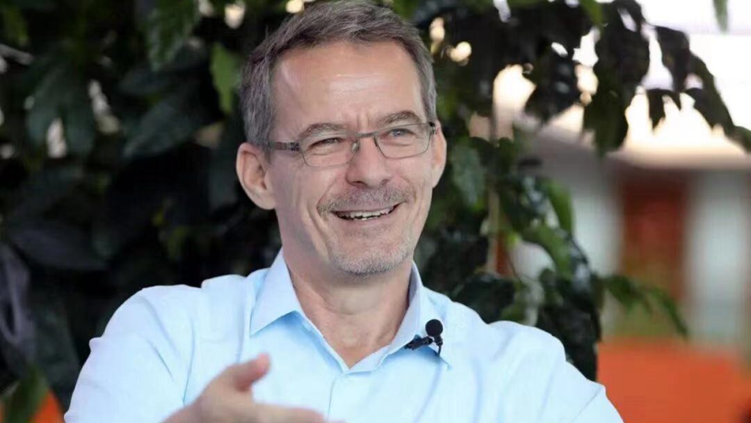 Smiling man with glasses wearing a light blue shirt.
