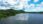 Floating solar panels on a lake surrounded by green hills under a blue sky.