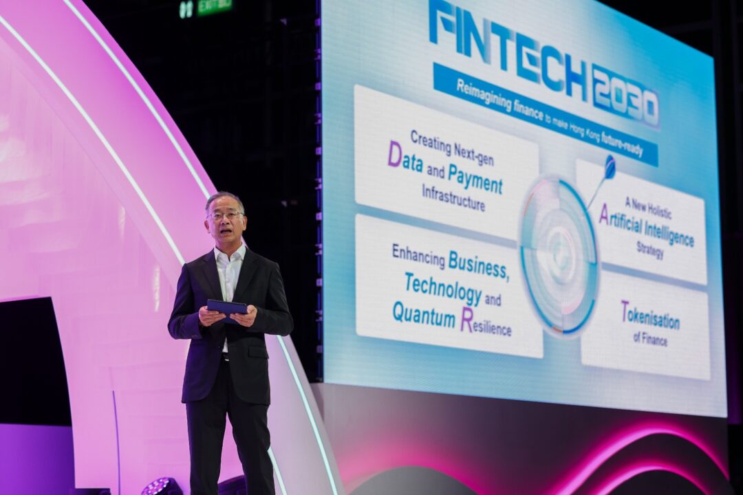 A man in a suit presents at a FinTech 2030 conference with a large digital screen behind him.