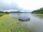A floating solar panel device on a lake surrounded by greenery under a cloudy sky.