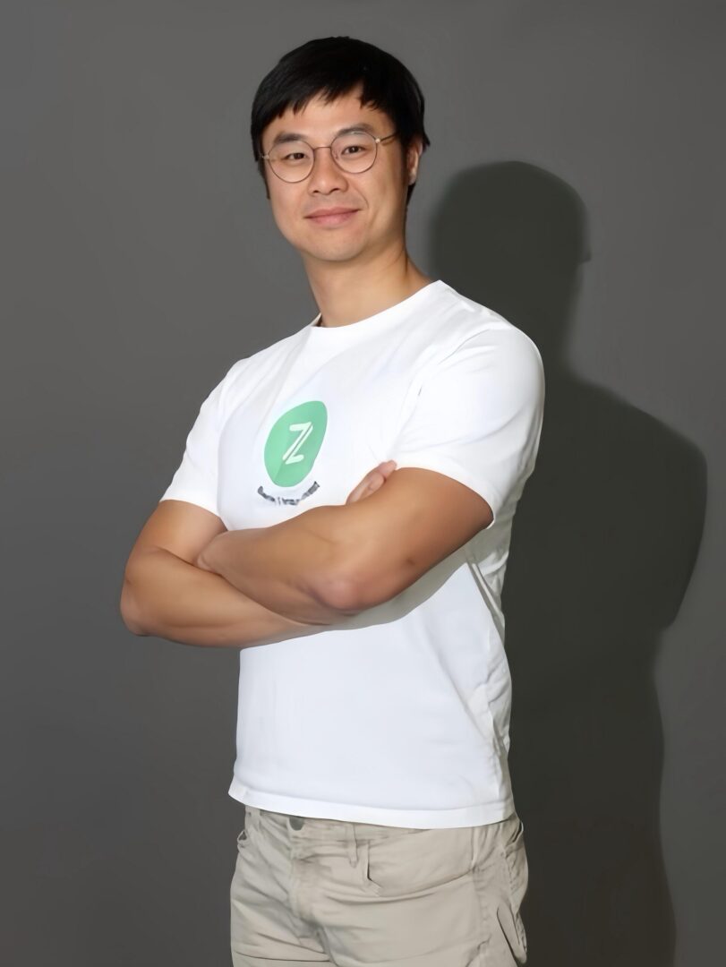 Man in white t-shirt with arms crossed, smiling confidently.